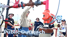 foreground text is "Public Outreach" and the background has people around an oil pipe